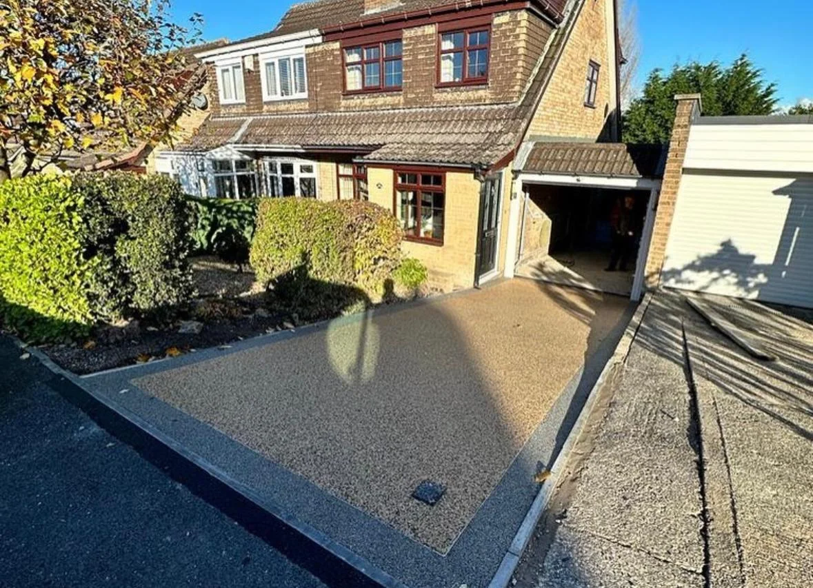 Warm resin driveway with contrasting borders outside a timber-fronted house